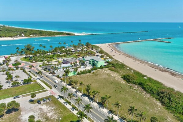 An aerial view of a coastal area with a road, buildings, and a beach.