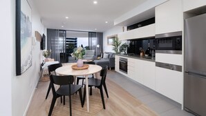 A modern kitchen with white cabinets, stainless steel appliances, and a dining area with a round table and chairs.