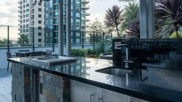 An outdoor kitchen area with a stone countertop, a sink, and a grill.