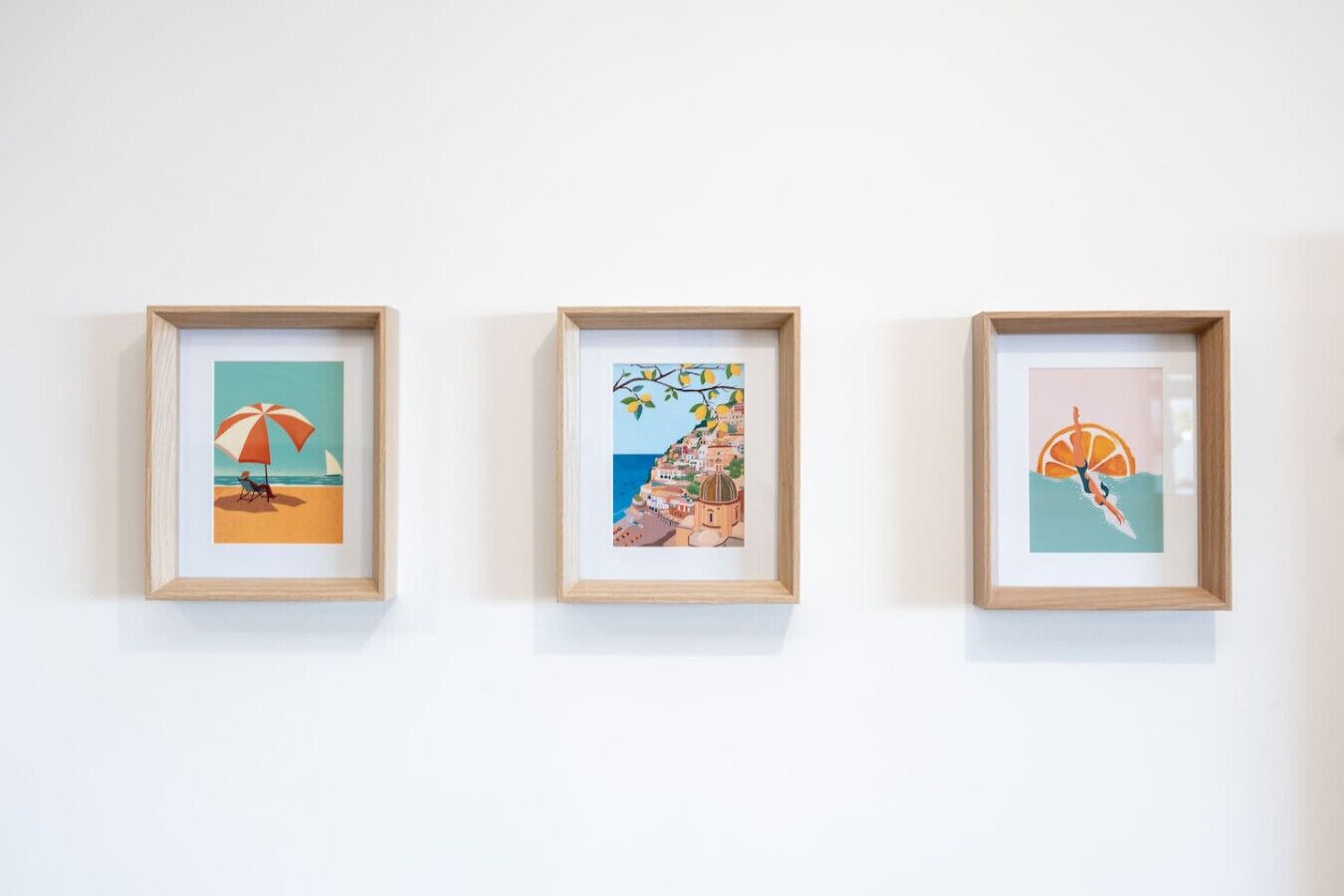 Trois œuvres d’art encadrées sont accrochées au mur.