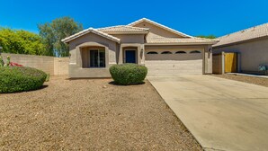 A single-story house with a garage, a small porch, and a gravel driveway.