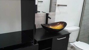 A modern bathroom with a black vanity, a large mirror, and a white toilet. - Beausejour Vista Studio1 (Gros Islet)