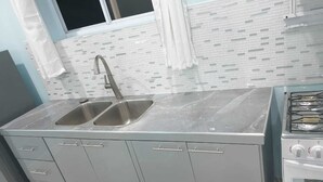 A kitchen with a double sink, stainless steel appliances, and a tiled backsplash. - Beausejour Vista Studio1 (Gros Islet)