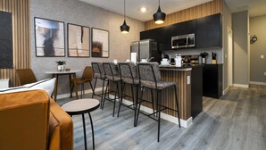 Una cocina moderna con una isla central, taburetes de bar y un comedor con mesa y sillas.