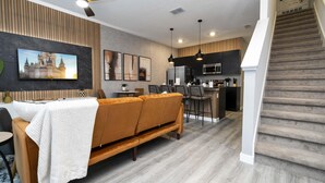 Una sala de estar moderna con un sofá, un comedor, una cocina y una escalera.