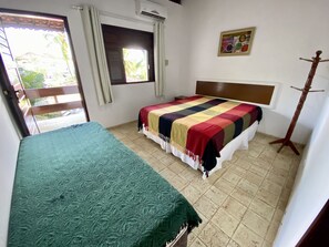 A room with a bed, a bench, a window, and a coat rack.
