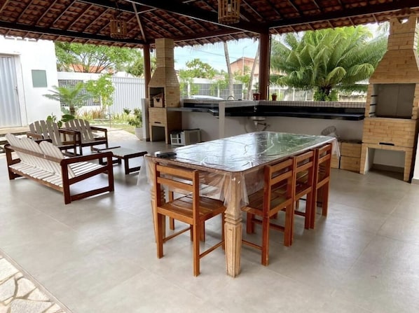 An outdoor kitchen area with a large island, wooden chairs, and a grill.