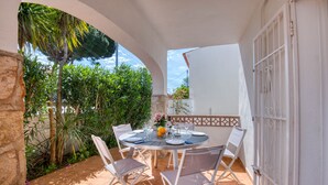 A round table with chairs, a white door, and a garden view. - LES HUPPES: Nice ground floor house in l'Escala with air-conditioning and large terrace (L'Escala)
