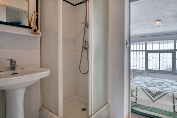 A bathroom with a shower, sink, and a bed visible through a window. - LES HUPPES: Nice ground floor house in l'Escala with air-conditioning and large terrace (L'Escala)