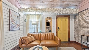 Una sala de estar acogedora con un sofá de cuero marrón, una mesa de centro redonda y una puerta amarilla.