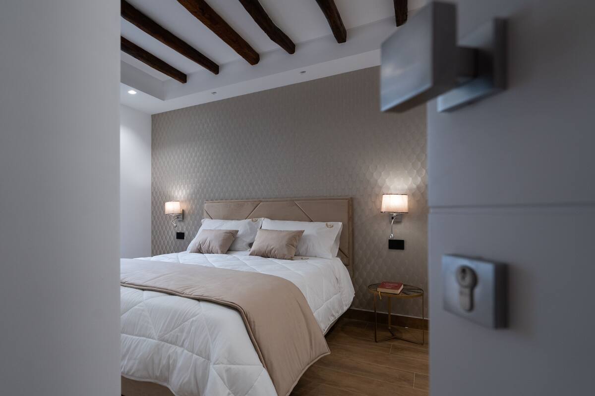 Ein modernes Schlafzimmer mit einem großen Bett, Holzbalkendecke und zwei Wandleuchten.