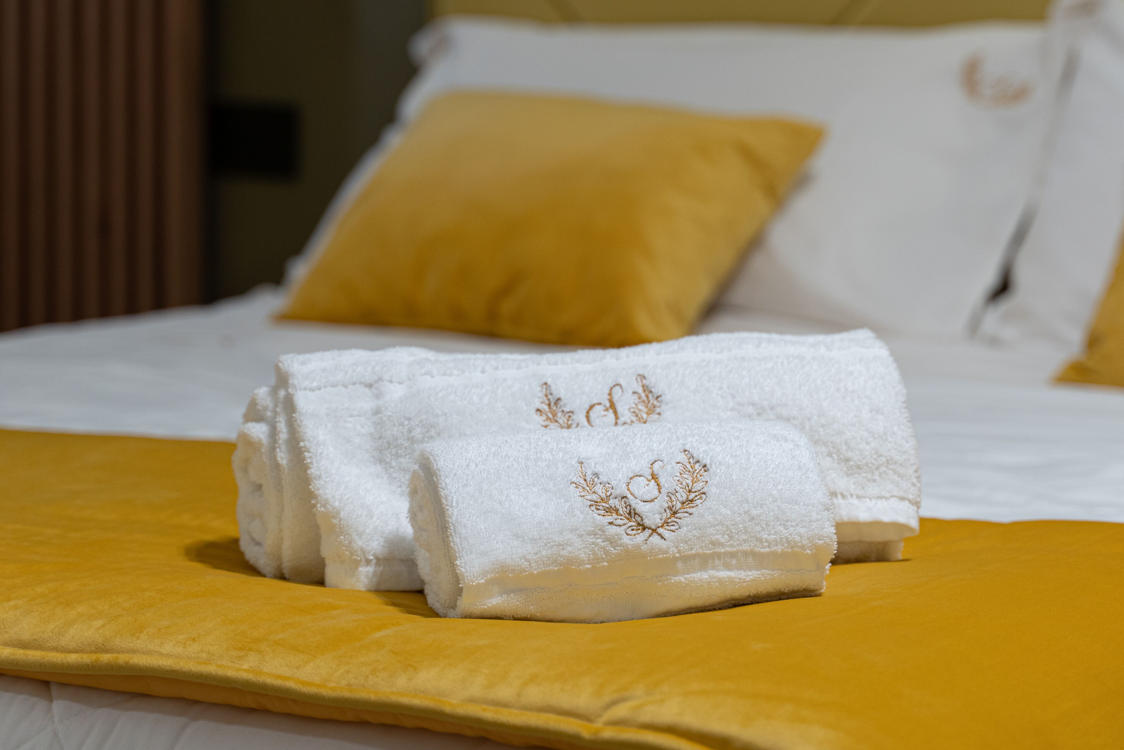 Una cama bien tendida con sábanas blancas y una manta amarilla.