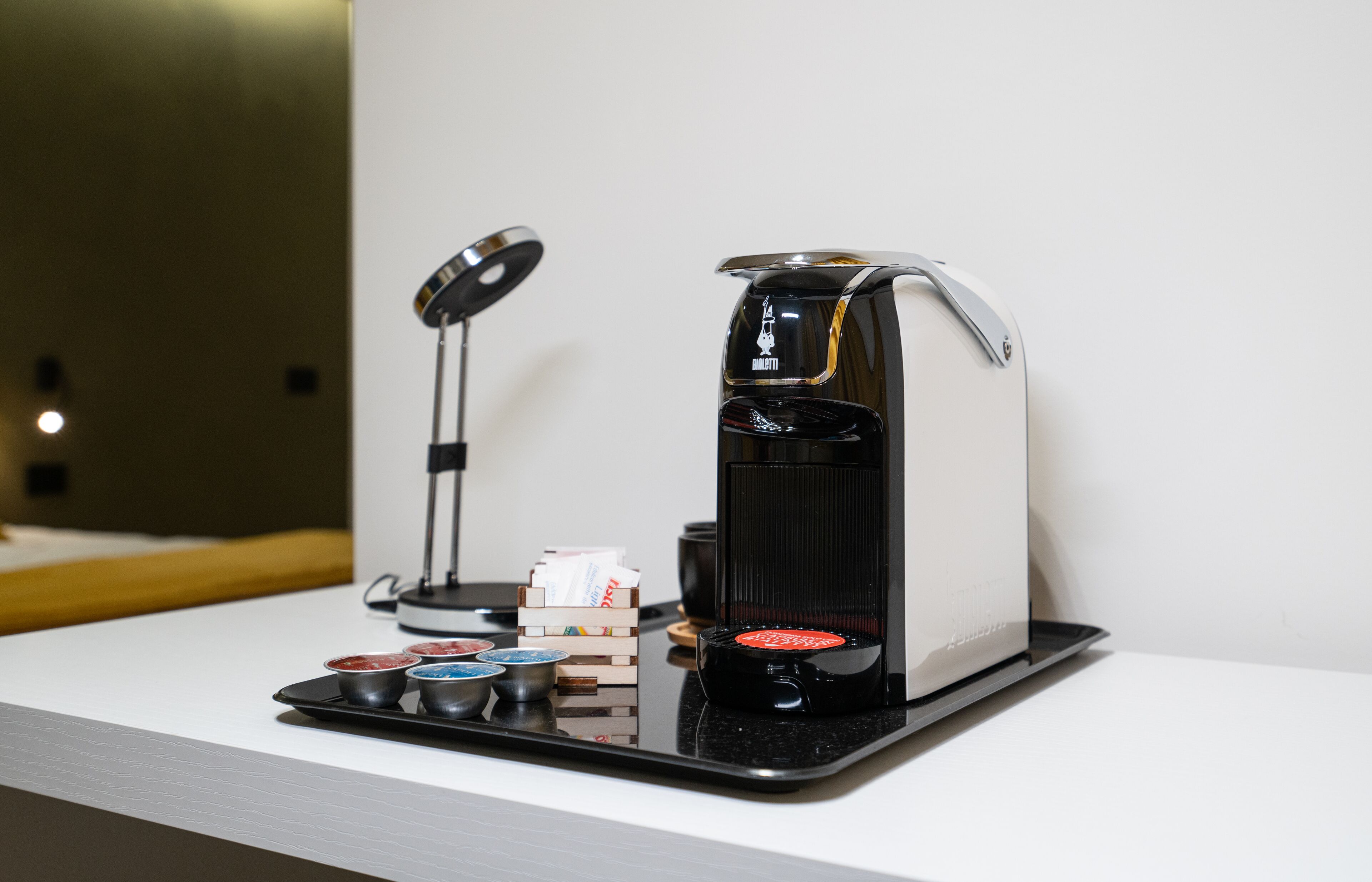 A coffee machine with a tray of coffee pods and a small stack of napkins on a white countertop.
