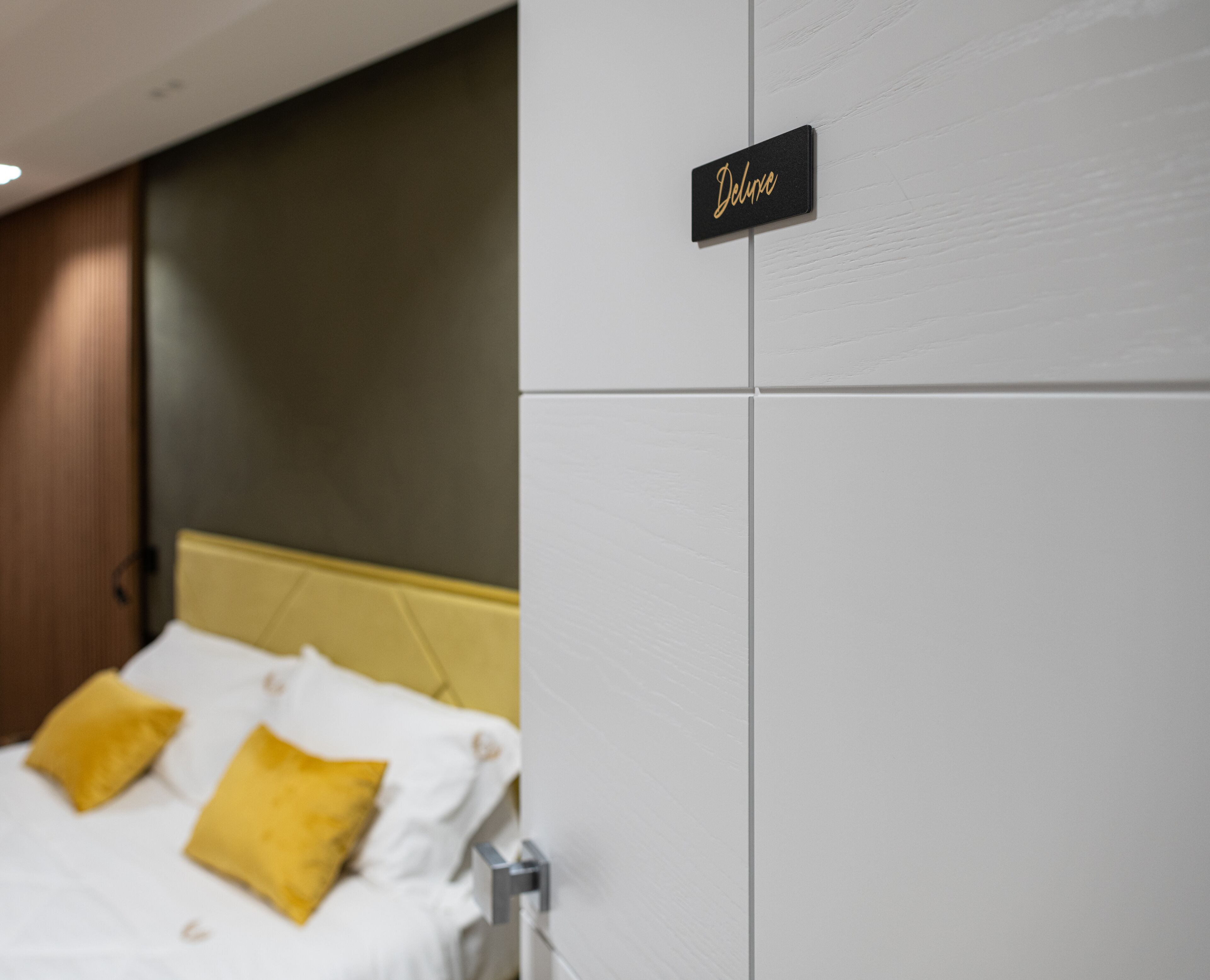 A hotel room with a bed, a sign reading "Deluxe", and a white wardrobe.