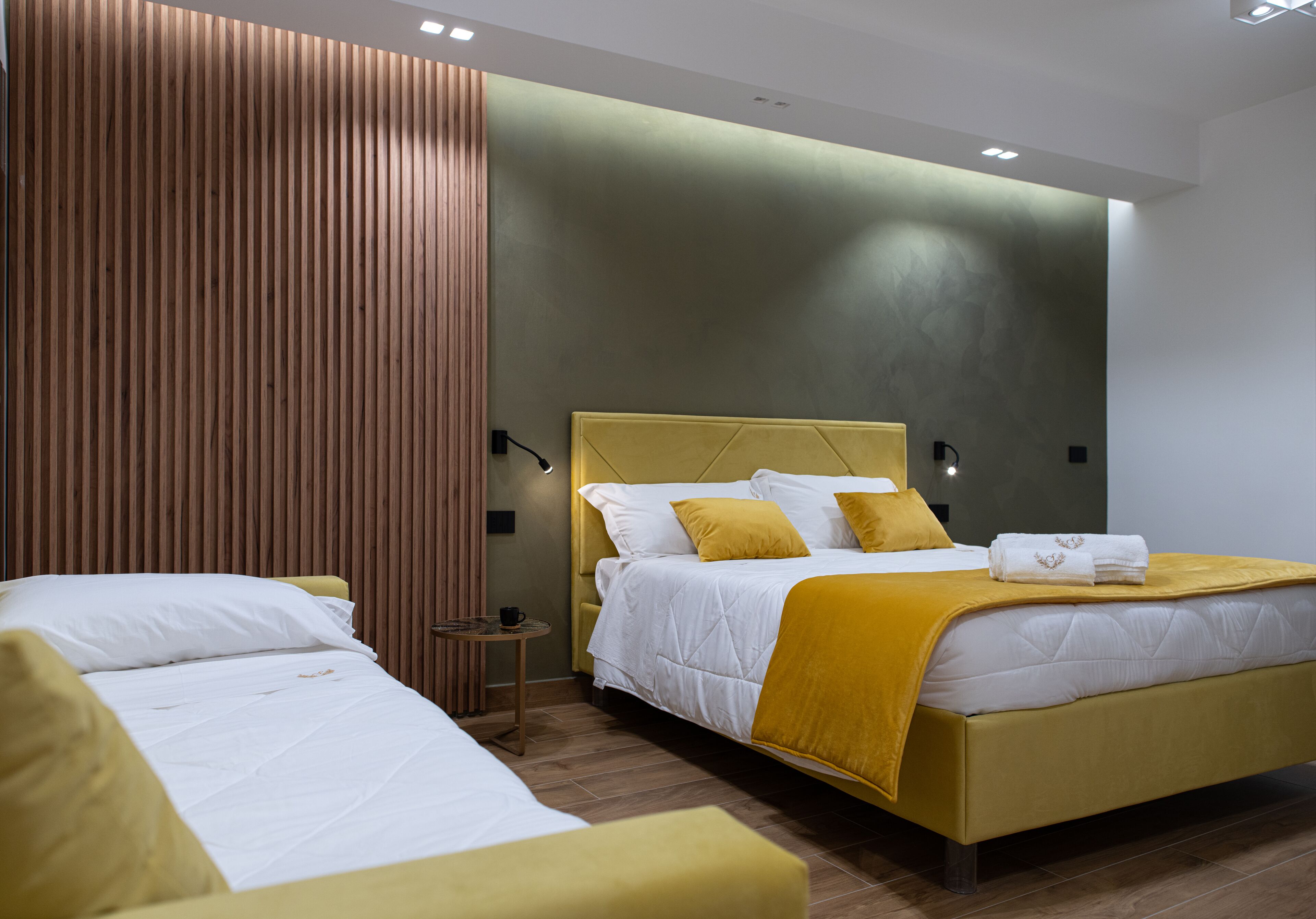 Ein modernes Hotelzimmer mit einem großen Bett, einer kleineren Couch und einer Wand mit Holzelementen.
