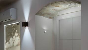 A hallway with a white door, a wall-mounted light, and a door with a black and white photograph.