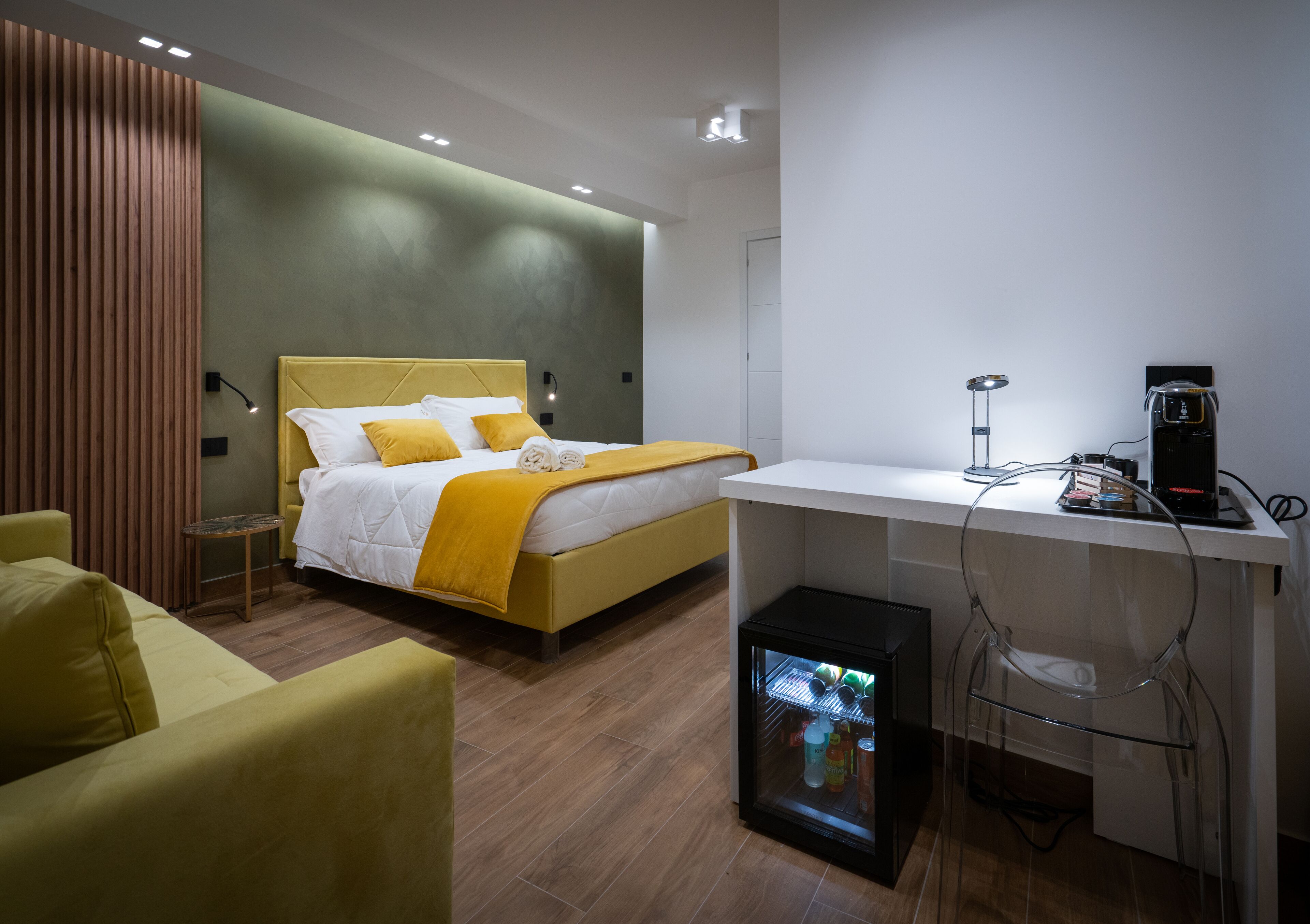 Une chambre d’hôtel moderne équipée d’un lit, d’un bureau, d’un réfrigérateur et d’une chaise.