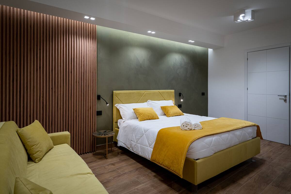 Ein modernes Schlafzimmer mit einem Bett, einem Sofa und einem kleinen Tisch.