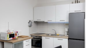 A modern kitchen with white cabinets, a stainless steel refrigerator, a microwave, an oven, and a sink. - Apartment Mia - Two Bedroom Apartment with Balcony (Split)