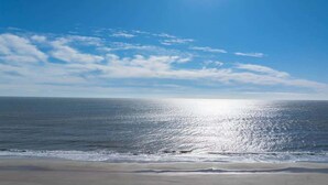 Une plage avec un ciel d égagé et la lumière du soleil se reflétant sur l’eau.