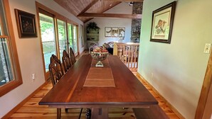 A long wooden dining table with benches, a chandelier, and framed pictures on the walls. - Beautiful Mountain View with Large Saltwater Pool (Landrum)