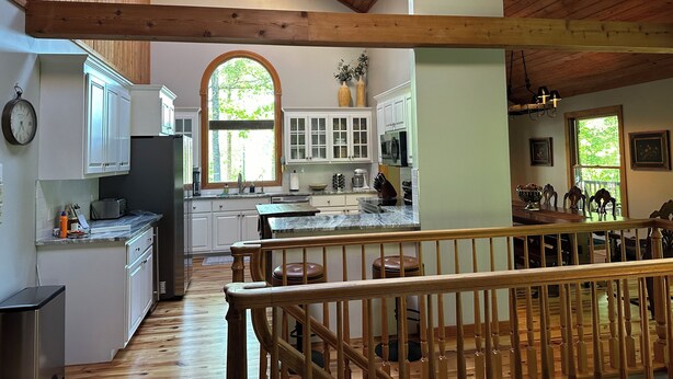 A spacious kitchen with wooden beams, white cabinets, and a large window. - Beautiful Mountain View with Large Saltwater Pool (Landrum)