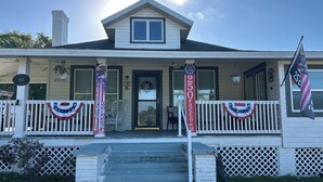 A house with a porch, steps, a flag, and a banner.