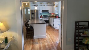 A modern kitchen with white cabinets, a stainless steel refrigerator, and a wooden island.