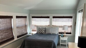 A bedroom with a bed, a ceiling fan, a nightstand, and a dresser.