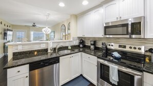 Una cocina moderna con armarios blancos, electrodomésticos de acero inoxidable y encimera de granito.