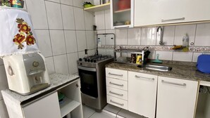 A kitchen with white cabinets, a gas stove, a microwave, and a coffee maker. - 3 quartos a 2 quadras da Praia (Maceió)