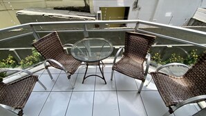 A balcony with wicker chairs and a glass table, surrounded by a metal railing. - 3 quartos a 2 quadras da Praia (Maceió)