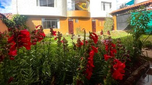 Een meerhoog gebouw met balkons en een tuin met rode bloemen.