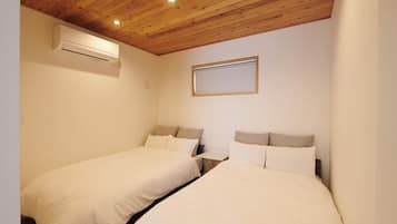 A bedroom with two beds, wooden ceiling, and an air conditioning unit.