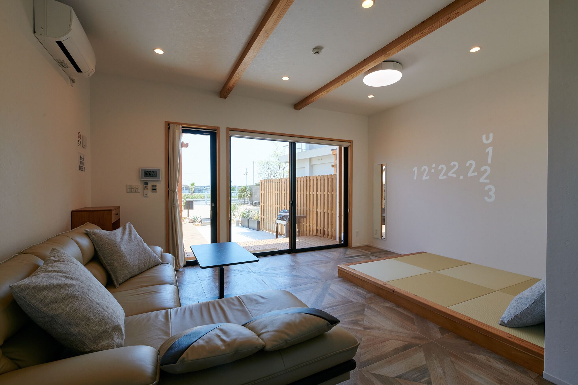 A modern living room with a sofa, a small table, and a tatami mat area.