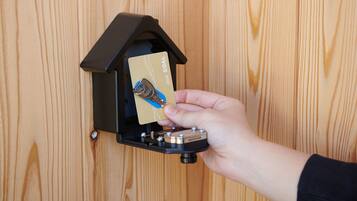 A hand inserting a key into a wooden door lock.