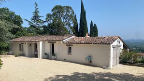 Una casa de dos plantas con techo de tejas, camino de grava y vistas del paisaje circundante.
