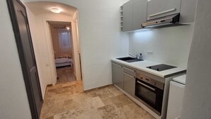 Una cocina compacta con fregadero, estufa y armarios.