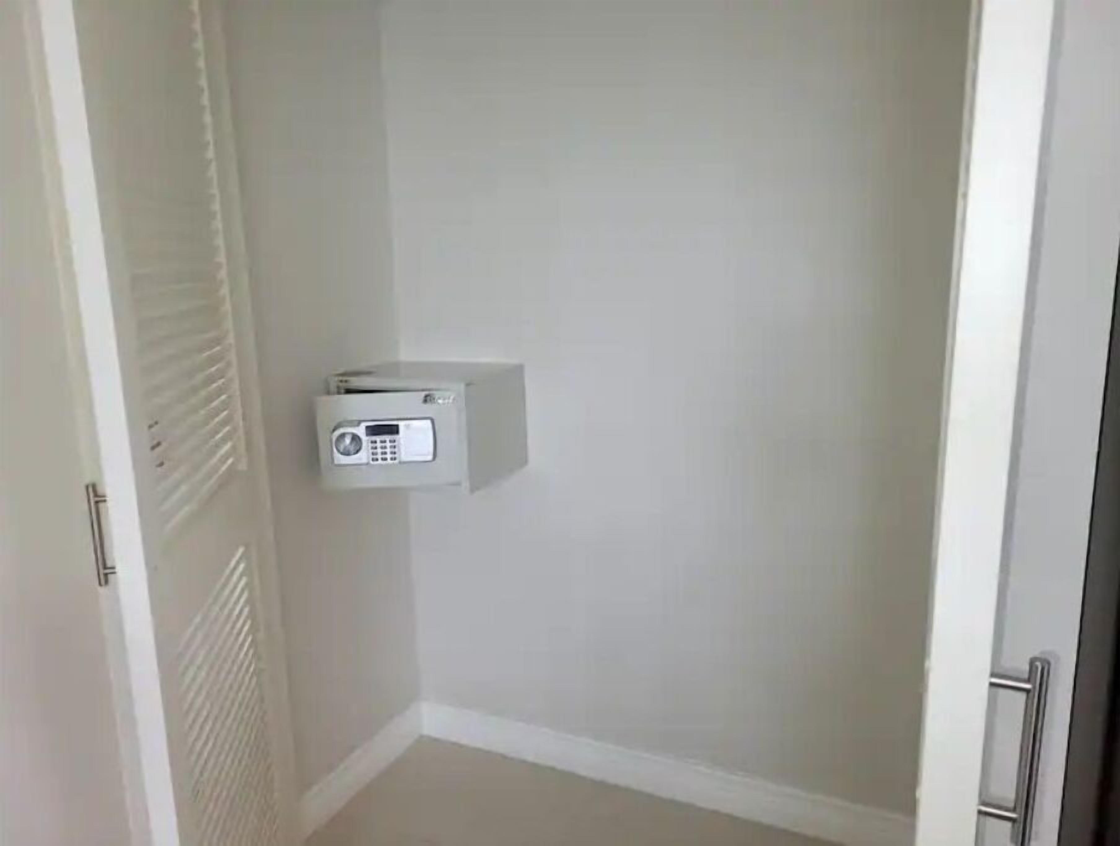 A small, white electrical box mounted on a wall in a corner of a room with a door and a vent.