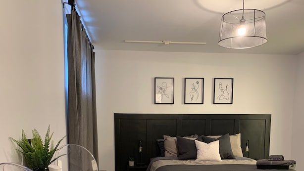 Una camera da letto moderna con un letto, una scrivania e una sedia. Tre opere d'arte incorniciate adornano la parete.
