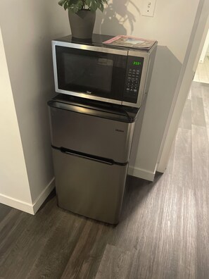 Eine kleine Küche mit einer Mikrowelle und einem Haier-Kühlschrank.
