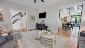 A spacious living room with a staircase, a dining area, and a view of the outdoors. - Hawthorn House Remodeled 3BR Walk to Town! (Colonial Beach)