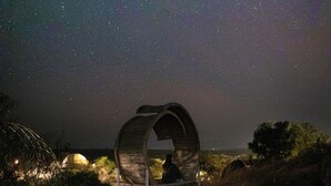 A rustic wooden structure with a curved roof, situated in a natural setting with a starry night sky above. - KUOOM SERENGETI (Serengeti)