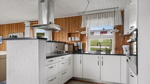 Uma cozinha moderna com armários brancos, bancada preta e uma janela com vista para uma casa.
