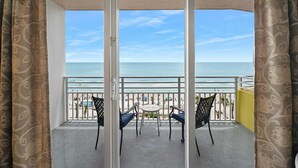 Un balcón con vista a la playa, que incluye dos sillas y una mesa.