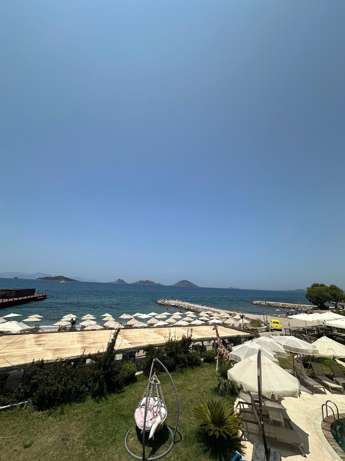 A coastal resort with outdoor seating and a swing chair, overlooking the sea.