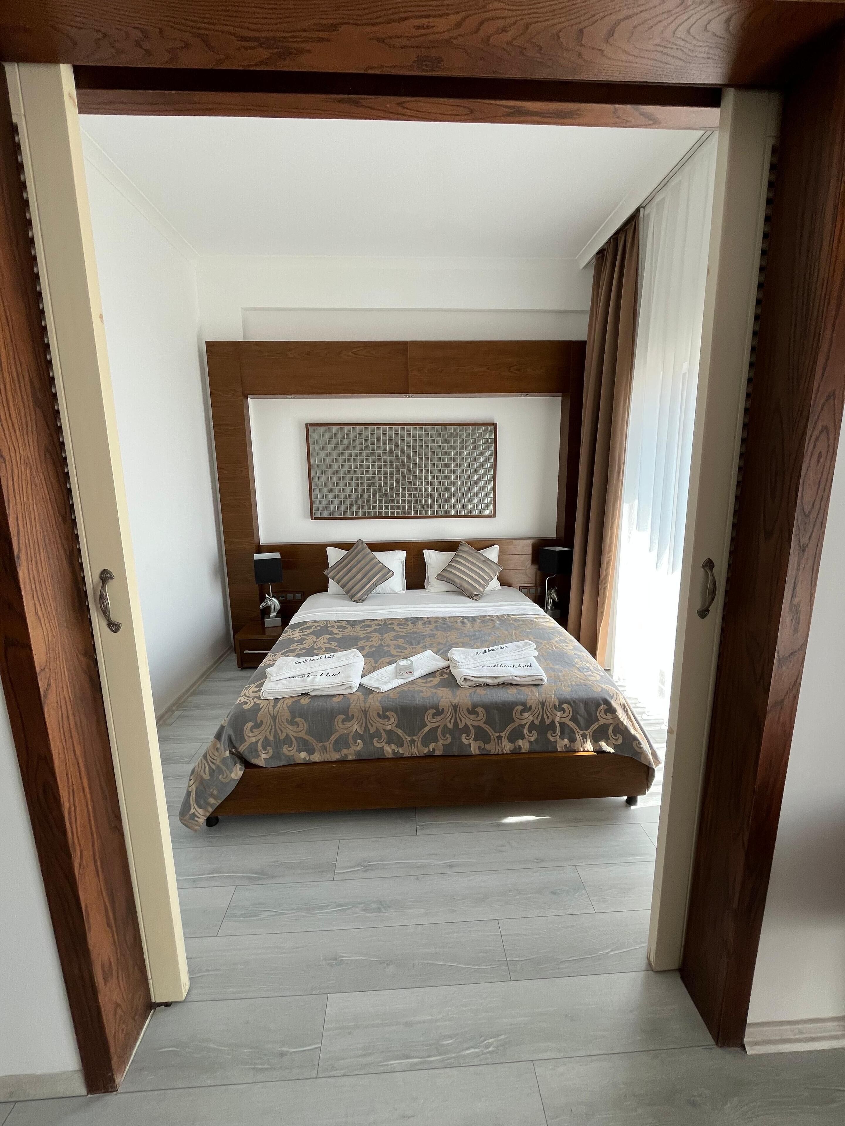 A modern bedroom with a large bed, wooden headboard, and a decorative wall piece.