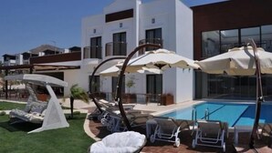 Un hôtel moderne doté d’une piscine, d’un espace extérieur aménagé et de parasols.