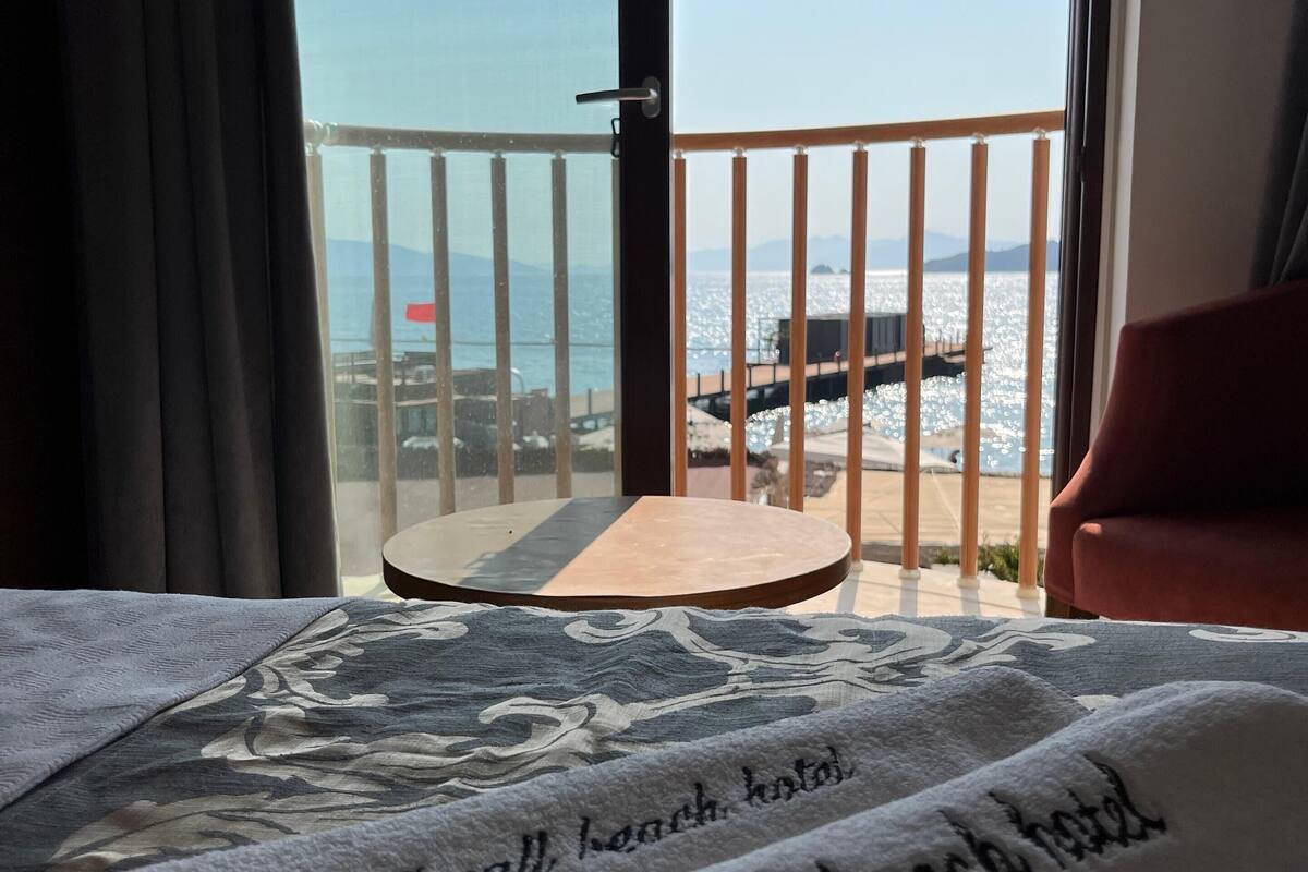 A hotel room with a balcony overlooking a beach.
