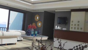 Un intérieur moderne avec un canapé blanc, une table basse ronde agrémentée de vases décoratifs et une grande fenêtre donnant sur la mer.